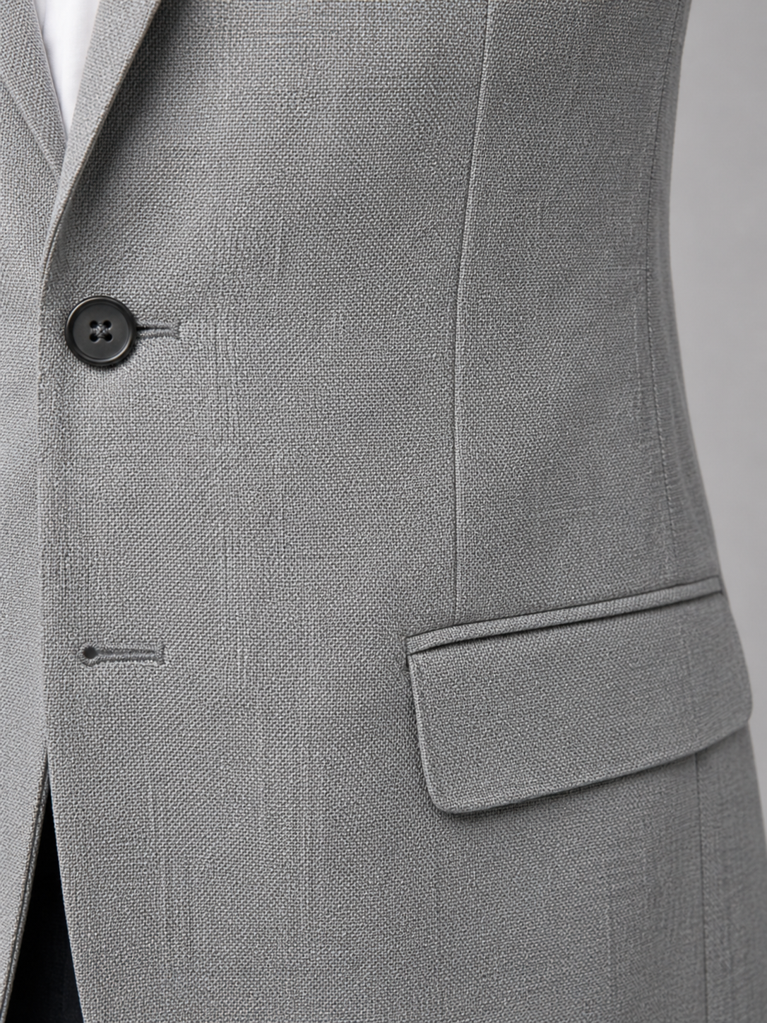 Close-up of a gray suit jacket with a button and pocket on a light gray background