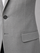 Close-up of a gray suit jacket with a button and pocket on a light gray background