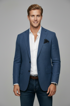 Man wearing a blue blazer over a white shirt with a gray background