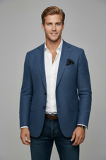 Man wearing a blue blazer over a white shirt with a gray background