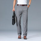 Person wearing gray pants and holding a black briefcase on a gray background