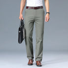 Person wearing olive green pants with a white shirt and brown shoes on a gray background