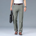Person wearing olive green pants with a white shirt and brown shoes on a gray background