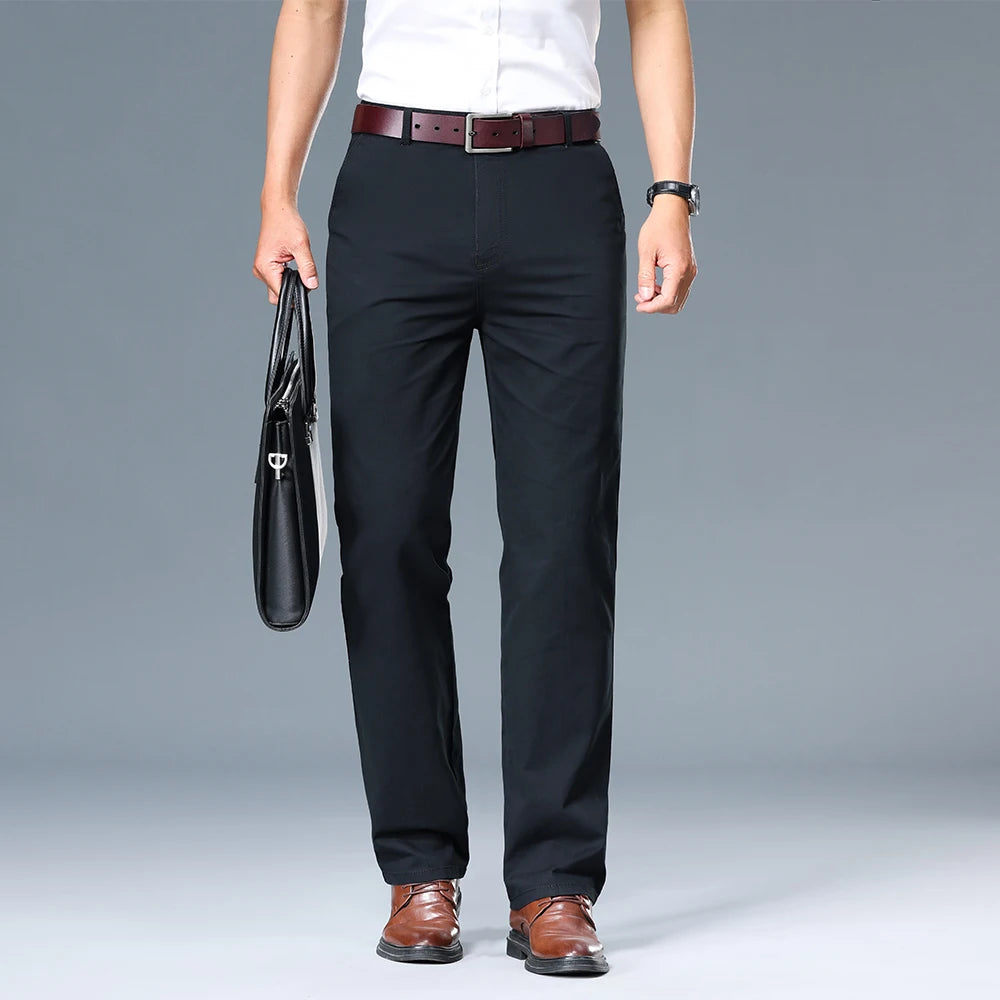 Person wearing black dress pants with a white shirt and brown shoes on a gray background