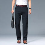 Person wearing black dress pants with a white shirt and brown shoes on a gray background