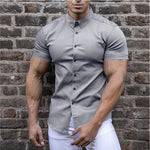 Man wearing a gray short-sleeve shirt against a brick wall