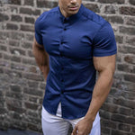 Man wearing a blue short-sleeve shirt against a brick wall
