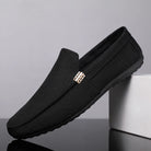 Black loafers with a gold buckle on a gray background