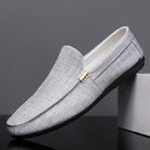 Gray loafers with a gold buckle on a dark background