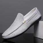 Gray loafers with a gold buckle on a dark background