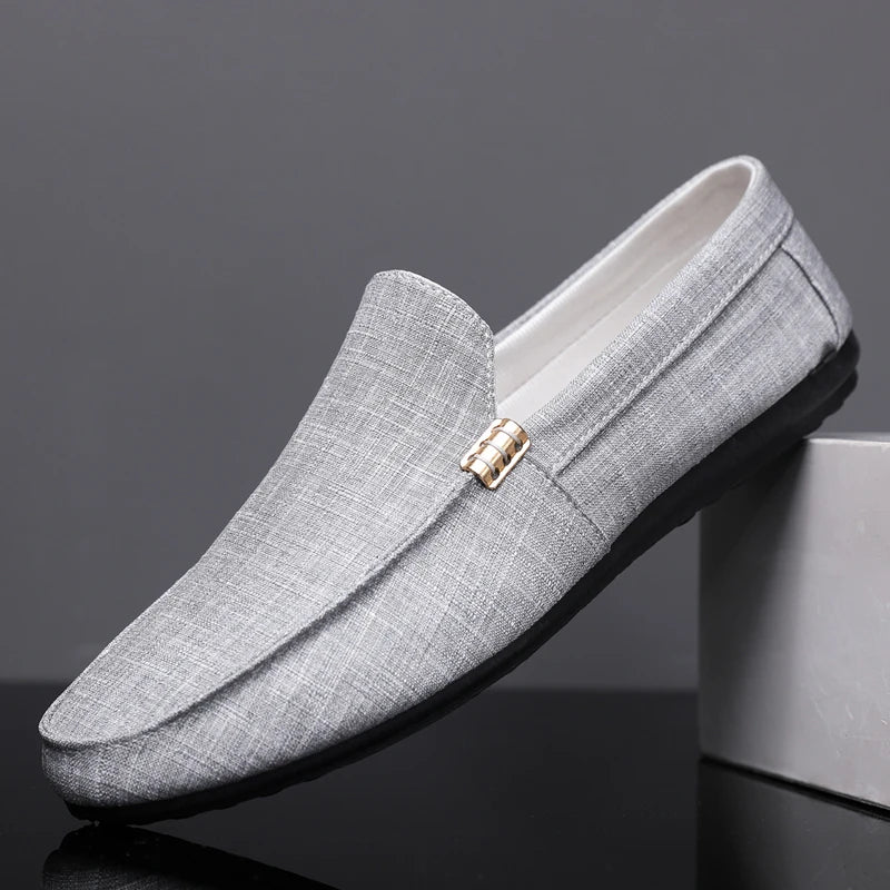Gray loafers with a gold buckle on a dark background