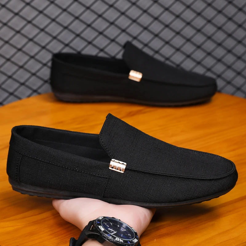 Black loafers with gold accents on a wooden surface, with a blurred background.