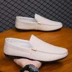 Beige loafers on a wooden surface with a grid-patterned wall in the background