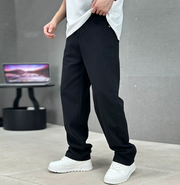 Person wearing black pants and white sneakers in a minimal indoor setting