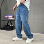 Person wearing blue jeans and white sneakers in a minimal indoor setting