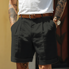 Person wearing black shorts with a white shirt and tattoos on arms and legs.