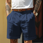 Person wearing navy shorts with a white shirt and brown belt against a blurred background