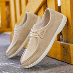 Beige slip-on shoes with white soles on a wooden surface