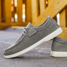 Gray casual shoes with white soles on a concrete surface.