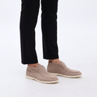 Beige slip-on shoes worn with black pants on a light background