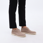 Beige slip-on shoes worn with black pants on a light background