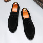 Pair of black loafers with brown insoles on a light gray background