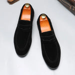 Pair of black loafers with brown insoles on a light gray background
