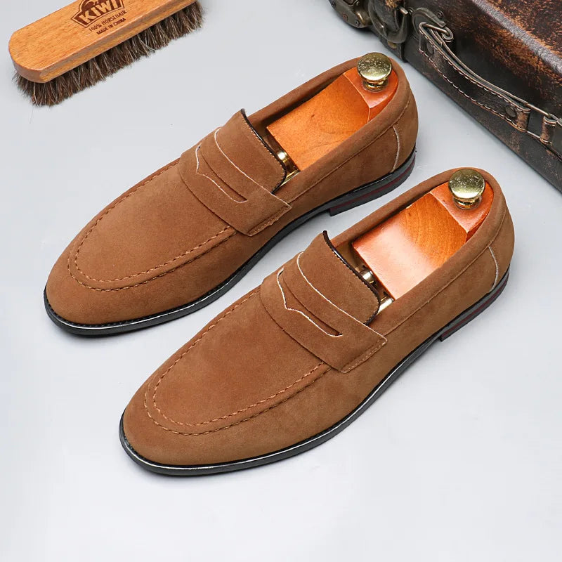 Pair of brown loafers with a brush and leather case on a light gray background