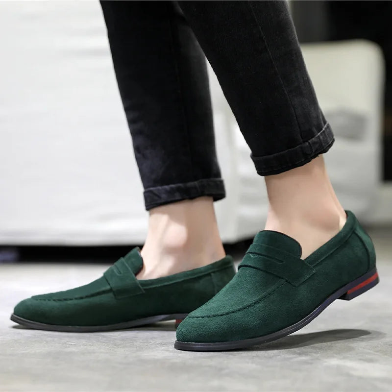 Green loafers worn with black pants on a neutral background
