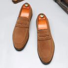 Pair of brown loafers with gold buttons on a light gray background