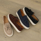 Four pairs of loafers in beige, brown, navy, and black on a wooden floor.