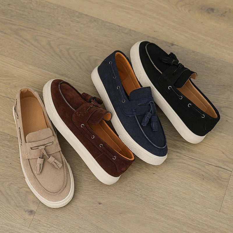 Four pairs of loafers in beige, brown, navy, and black on a wooden floor.
