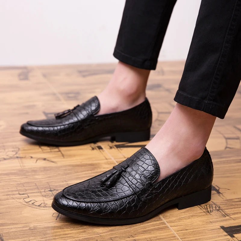 Black leather loafers worn on a wooden floor