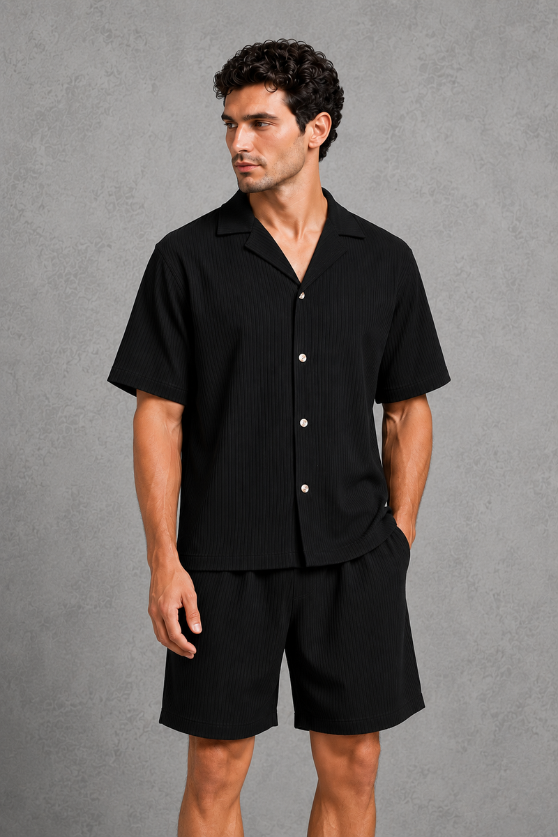 Man wearing a black button-up shirt and shorts against a gray background