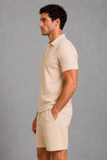 Man wearing a beige polo shirt and shorts against a gray background