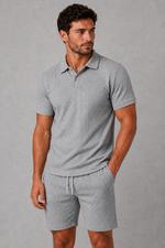 Man wearing a gray polo shirt and shorts against a gray background