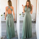 Woman wearing a green maxi dress with a backless design, standing in a bright room.