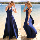 Woman in a blue dress standing on a beach with water in the background