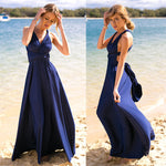 Woman in a blue dress standing on a beach with water in the background