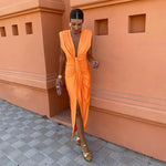 Woman in an orange dress standing against a terracotta wall.