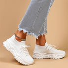 White sneakers worn with light blue jeans on a beige background