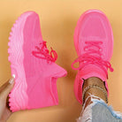Pair of bright pink sneakers on a beige background