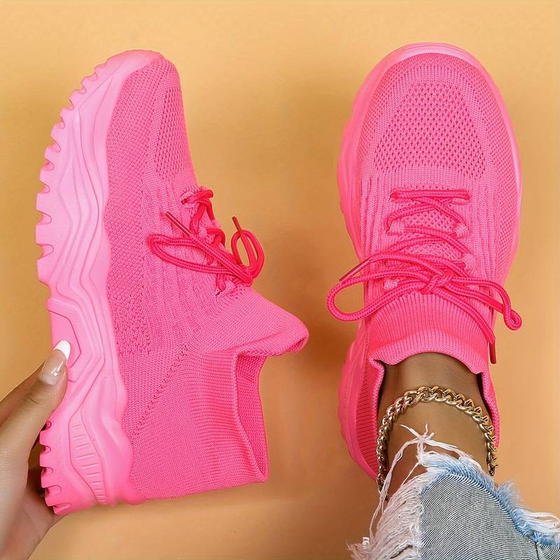 Pair of bright pink sneakers on a beige background