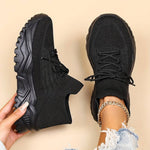 Black sneakers being held against a beige background