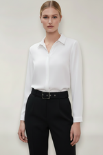 Person wearing a white shirt and black pants against a plain background