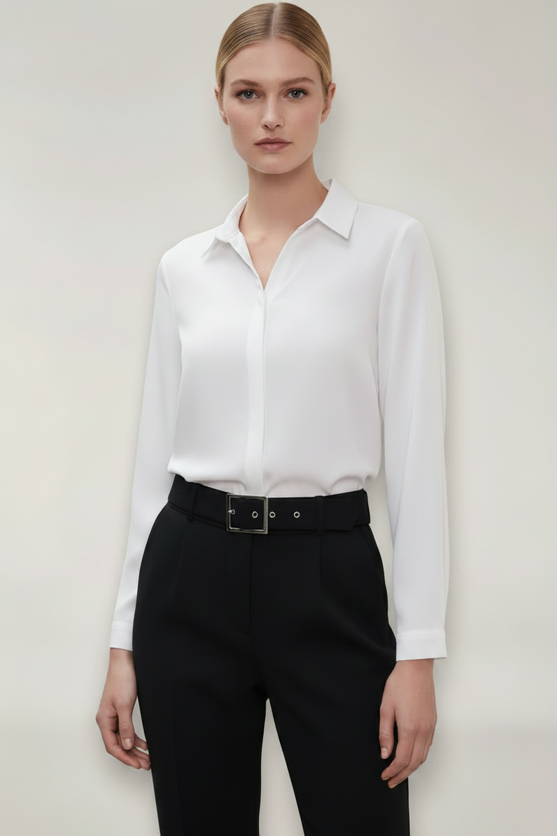 Person wearing a white shirt and black pants against a plain background
