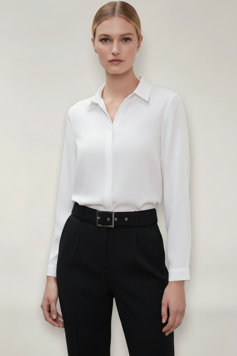 Person wearing a white shirt and black pants against a plain background