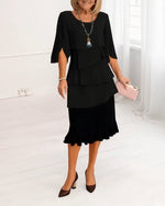 Woman wearing a black dress with ruffled layers on a white background