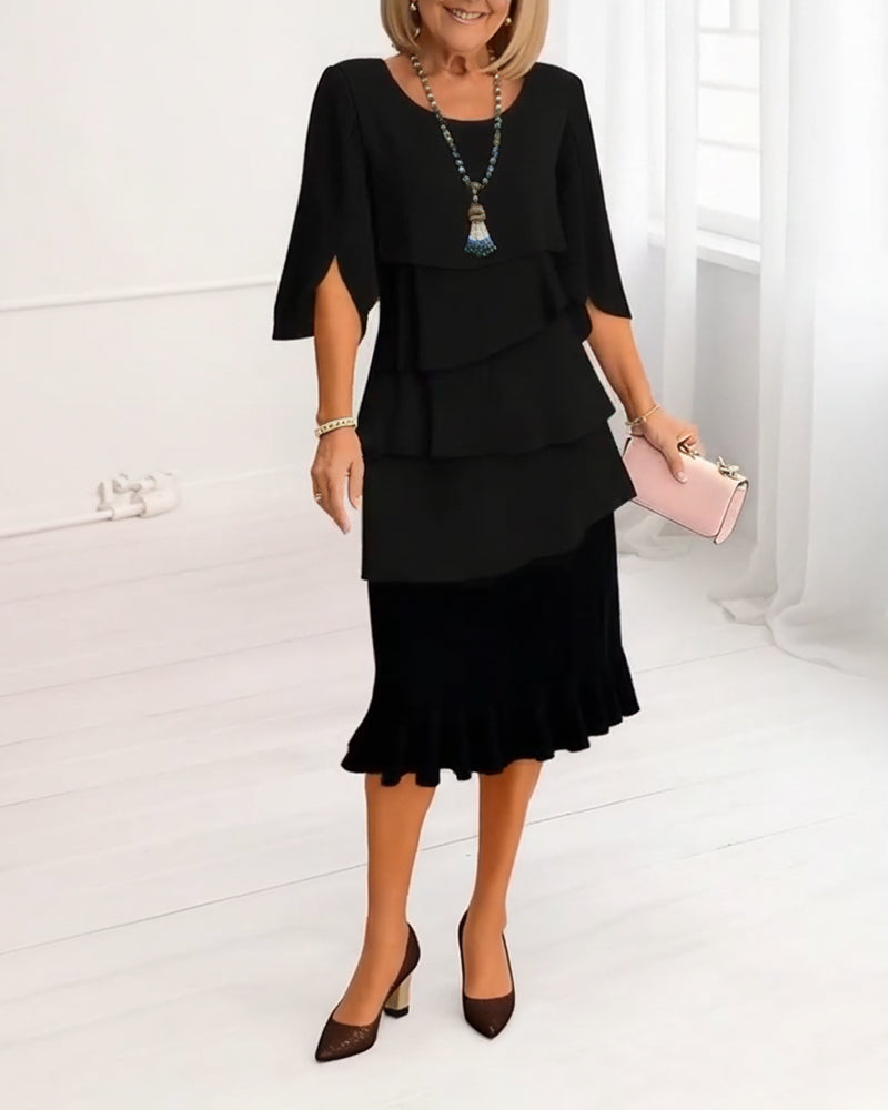 Woman wearing a black dress with ruffled layers on a white background