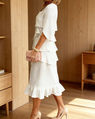 Woman wearing a white ruffled dress in a wooden interior setting